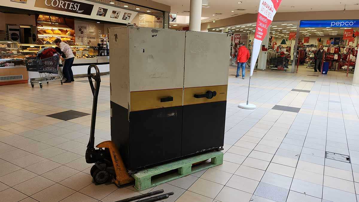 Páncélszekrény szállítása bevásárlóközpontban raklapemelővel és szakszerű rögzítéssel